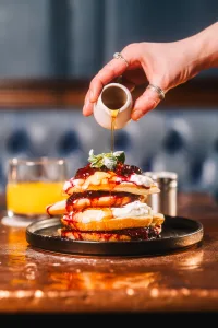 Stack of fluffy pancakes covered In berry compote and maple syrup. Available in York's iconic pub Trembling Madness Lendal